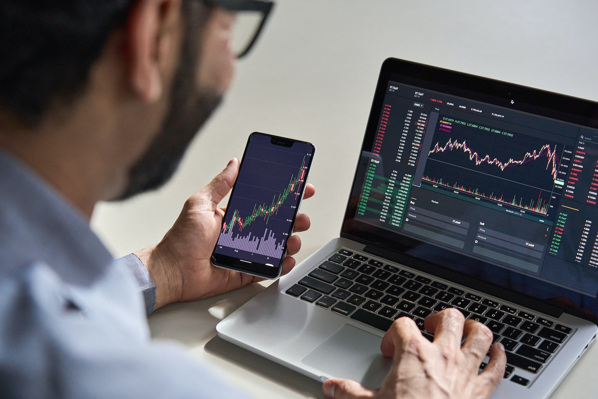 Trader checking live market data on phone and laptop